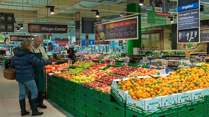 Los clientes miran la fruta en Real iluminada mediante soluciones para supermercados de Philips