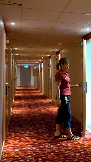 Una mujer en un pasillo del Hotel Spar, iluminado mediante iluminación de hoteles de Philips