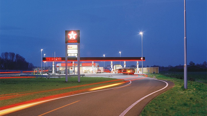Gasolinera Texaco en la autopista, con una iluminación atractiva, al atardecer - iluminación exterior llamativa